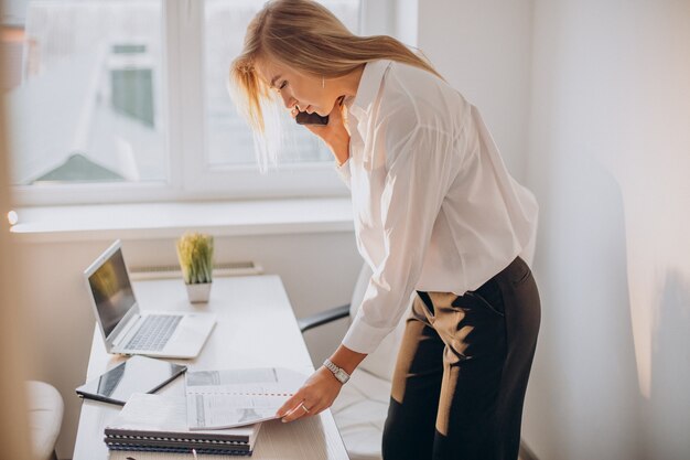 Jeune femme d'affaires à l'aide de téléphone au bureau