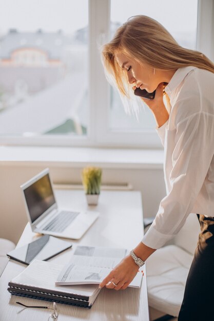 Jeune femme d'affaires à l'aide de téléphone au bureau