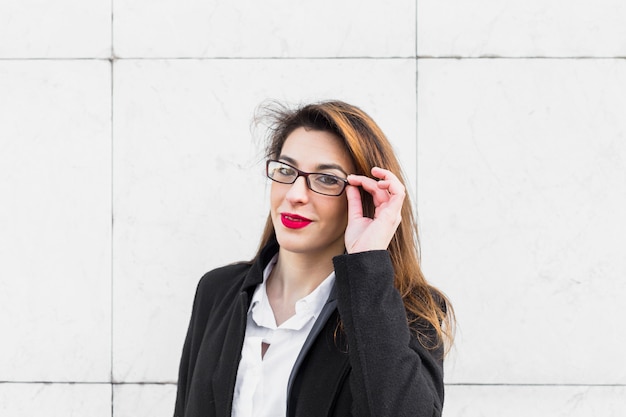 Photo gratuite jeune femme d'affaires ajustant des lunettes à l'extérieur