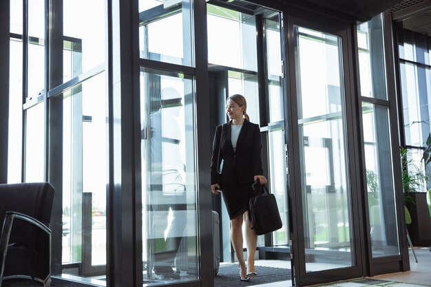 Jeune femme d'affaires en attente de départ à l'aéroport, voyage de travail, mode de vie professionnel.