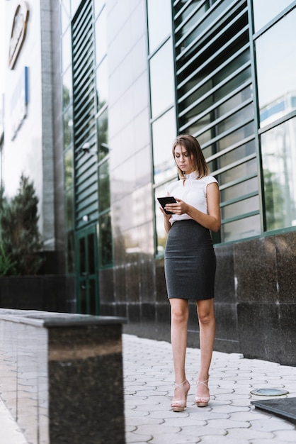 Une jeune femme d&#39;affaires attrayante à l&#39;aide de smartphone à l&#39;extérieur