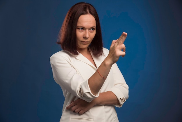 Jeune femme d'affaires en blazer blanc en forme de pistolet.