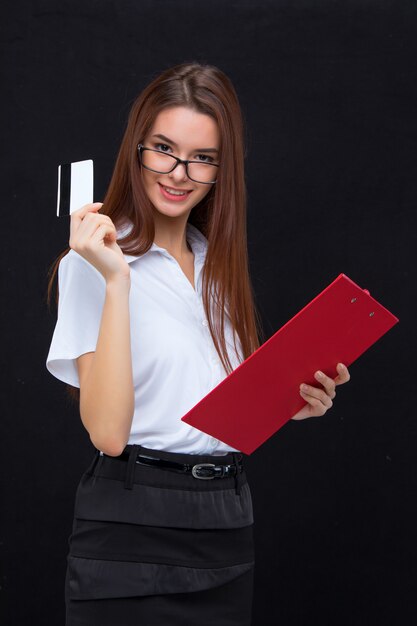 La jeune femme d'affaires avec carte de crédit et tablette pour notes sur mur gris