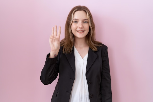 Photo gratuite jeune femme d'affaires caucasienne portant une veste noire montrant et pointant vers le haut avec les doigts numéro trois tout en souriant confiant et heureux