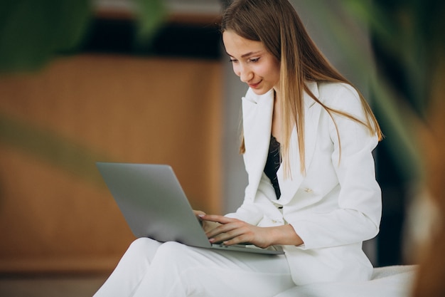 Jeune femme d'affaires en costume blanc travaillant sur un ordinateur