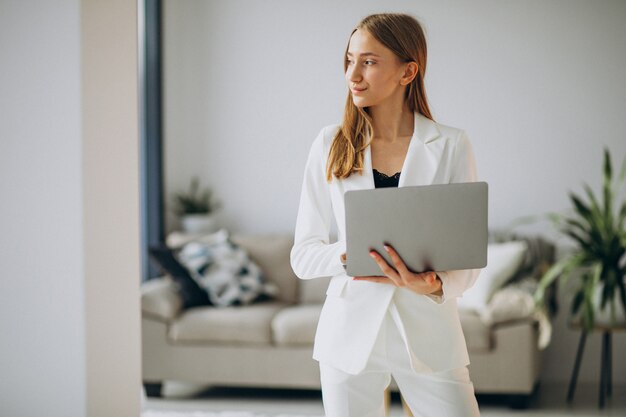 Jeune femme d'affaires en costume blanc travaillant sur un ordinateur