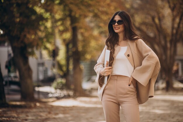 Jeune femme d'affaires en costume avec ordinateur portable dans la rue