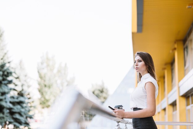 Jeune, femme affaires, debout, balcon, tenue, téléphone portable, et, tasse à café