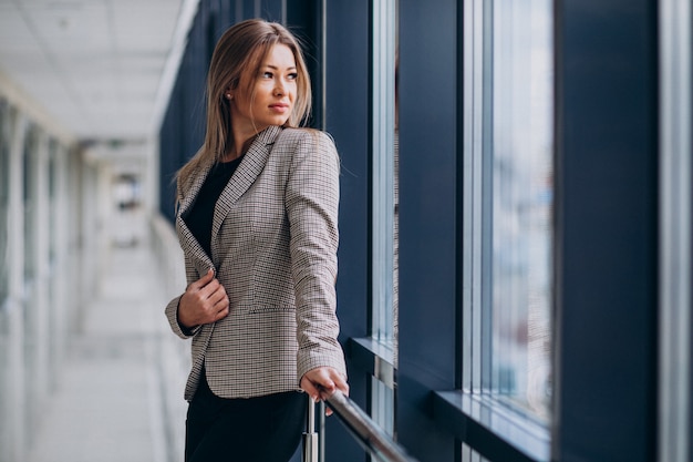 Jeune femme d'affaires debout près de la fenêtre dans un bureau