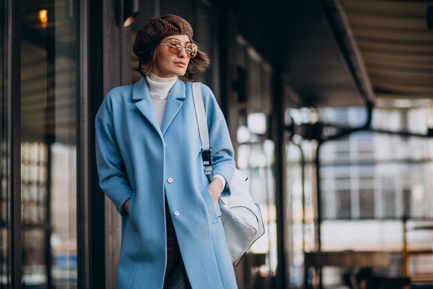 Jeune femme d'affaires en manteau bleu par le café
