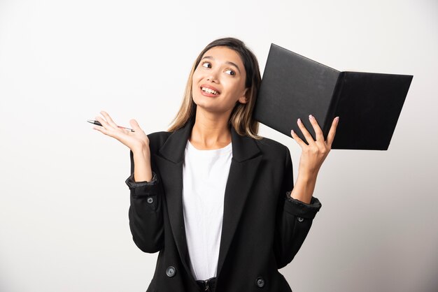 Jeune femme d'affaires montrant un presse-papiers noir.