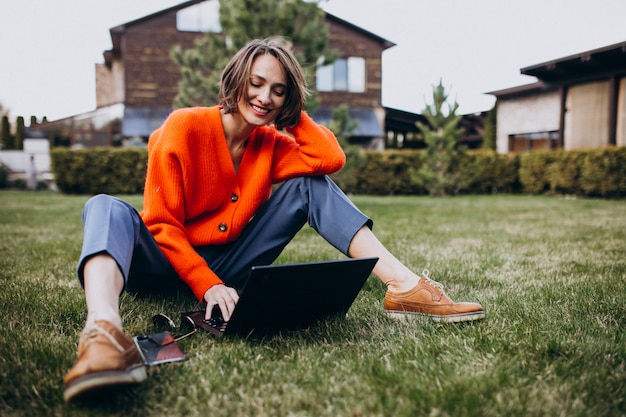 Jeune femme d'affaires avec ordinateur portable sur l'herbe