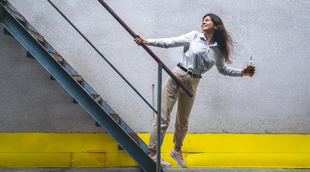 Photo gratuite jeune femme d'affaires près des escaliers avec une tasse de café