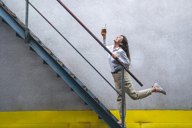 Jeune femme d'affaires près des escaliers avec une tasse de café