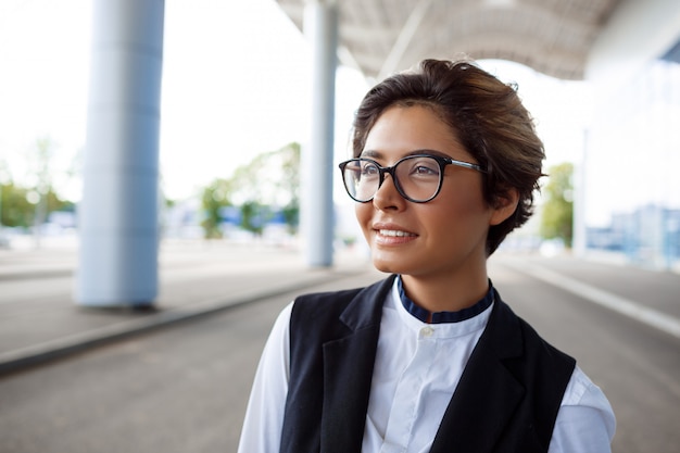 Jeune femme d'affaires prospère souriant, debout près du centre d'affaires