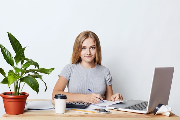 Jeune femme d'affaires, signature de documents tout en étant assis à table sur son lieu de travail