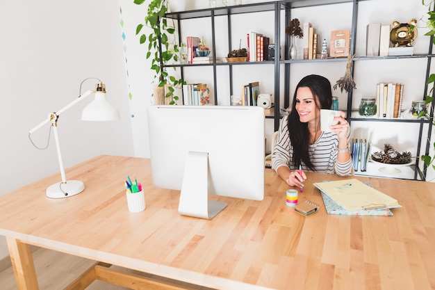 Jeune femme d&#39;affaires souriant tout en travaillant avec son ordinateur