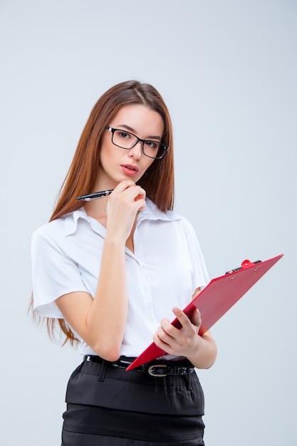 La jeune femme d'affaires avec un stylo et une tablette pour des notes sur gris