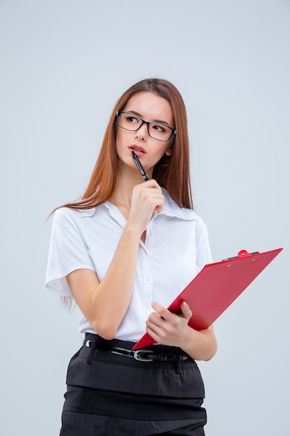 La jeune femme d'affaires avec stylo et tablette pour notes sur mur gris