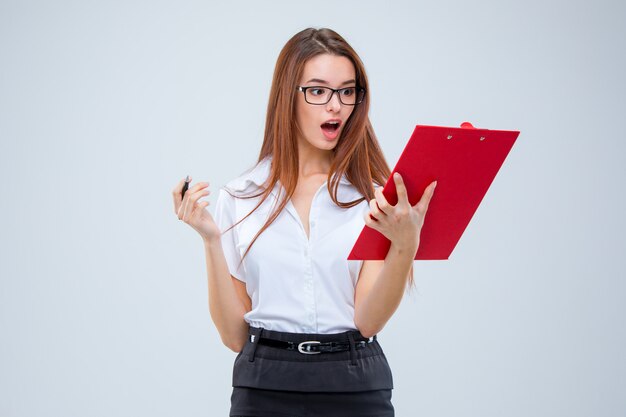 La jeune femme d'affaires avec stylo et tablette pour notes sur mur gris