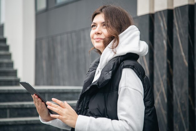 Jeune femme d'affaires avec une tablette sur le fond du bâtiment