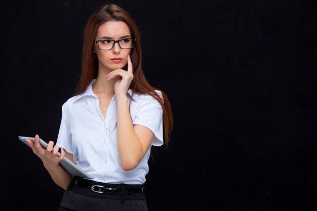 La jeune femme d'affaires avec tablette sur fond noir