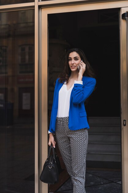 Jeune femme d&#39;affaires avec un téléphone mobile et sac à main