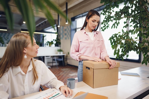 Jeune femme d'affaires tenant une boîte d'effets personnels sur le point de quitter ses fonctions après avoir quitté son emploi