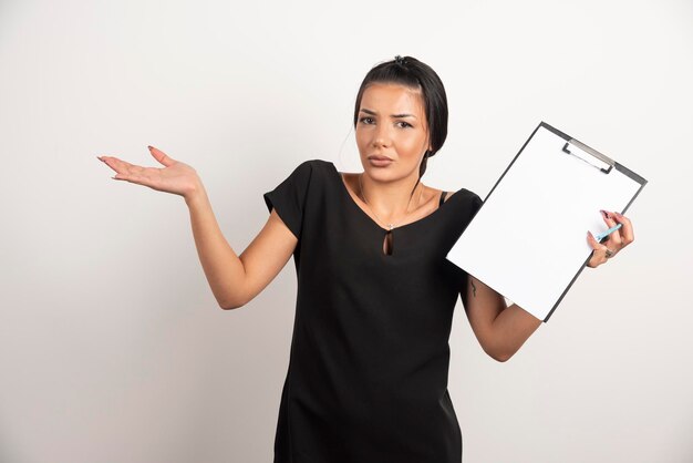 Jeune femme d'affaires tenant le presse-papiers sur le mur blanc.