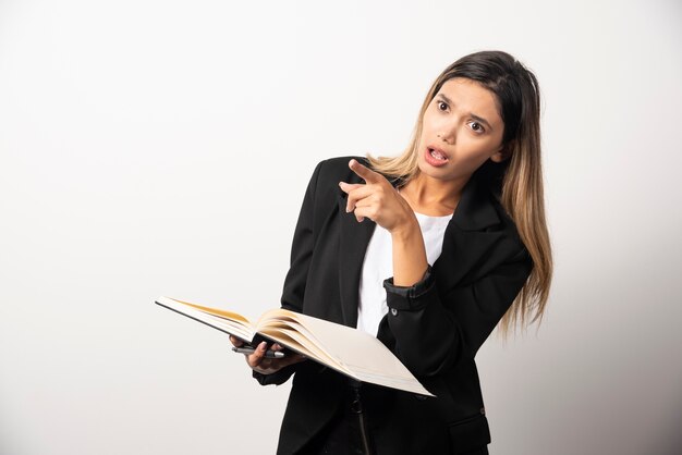 Jeune femme d'affaires tenant un presse-papiers ouvert avec un crayon.