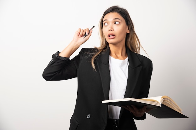 Jeune femme d'affaires tenant un presse-papiers ouvert avec un crayon.