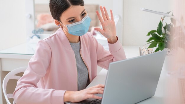 Jeune femme d'affaires travaillant à domicile et portant un masque