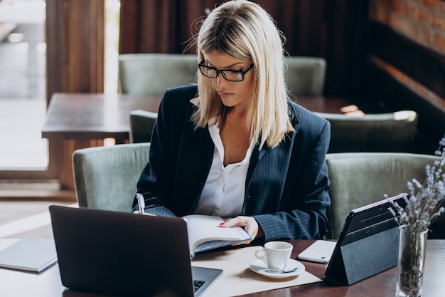 Jeune femme d'affaires travaillant sur ordinateur dans un café