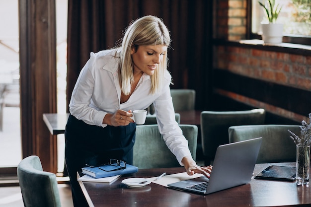 Jeune femme d'affaires travaillant sur ordinateur dans un café