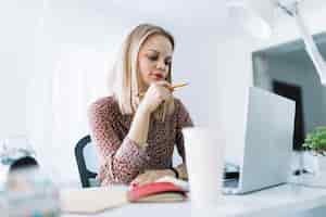 Photo gratuite jeune femme d'affaires travaillant sur un ordinateur portable au bureau