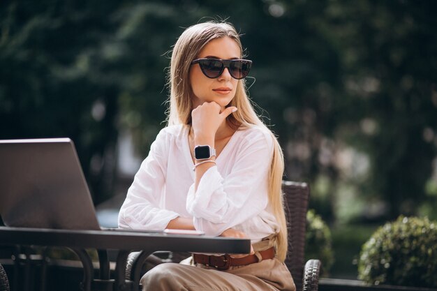 Jeune femme d'affaires travaillant sur un ordinateur portable à l'extérieur dans un café