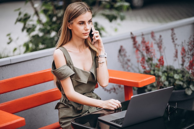 Jeune femme d'affaires travaillant sur un ordinateur portable à l'extérieur dans un café