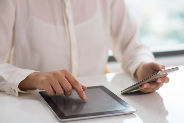 Jeune femme d&#39;affaires travaillant avec une tablette pc consultant un smartphone