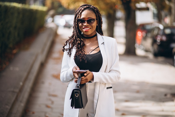 Photo gratuit jeune femme africaine en costume blanc à l'aide de téléphone