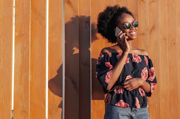 Jeune femme africaine souriante tout en parlant au téléphone