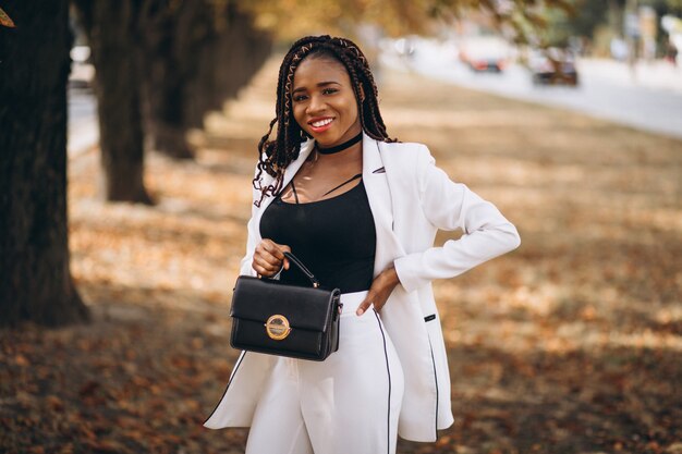 Jeune femme africaine vêtue d'un costume blanc dans le parc