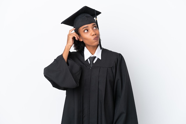 Jeune femme afro-américaine diplômée d'université isolée sur fond blanc ayant des doutes et avec une expression de visage confuse