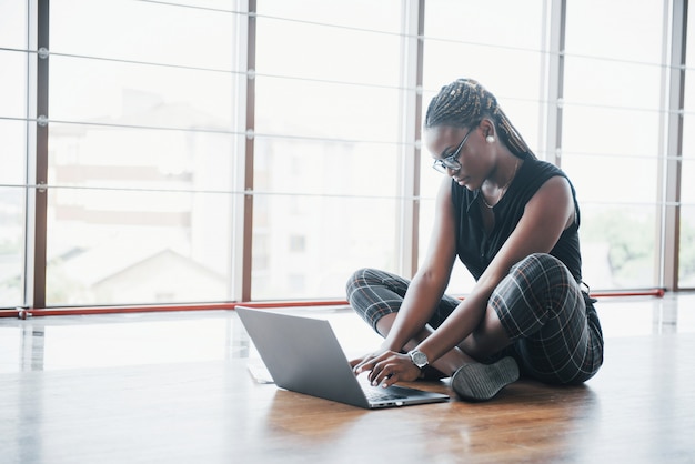 Une jeune femme afro-américaine est heureuse avec un ordinateur portable.