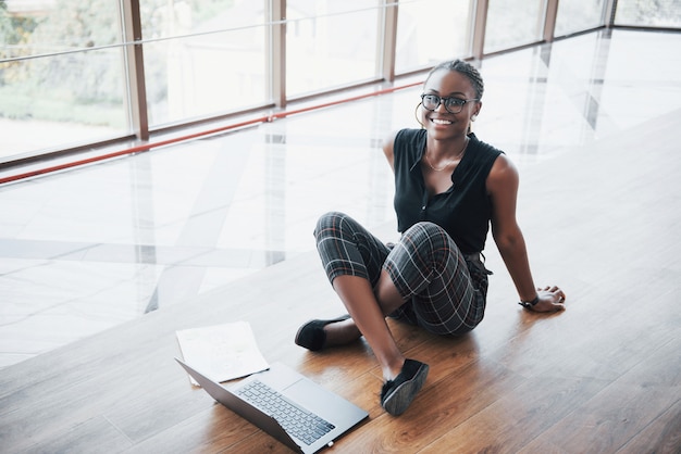 Photo gratuite une jeune femme afro-américaine est heureuse avec un ordinateur portable.