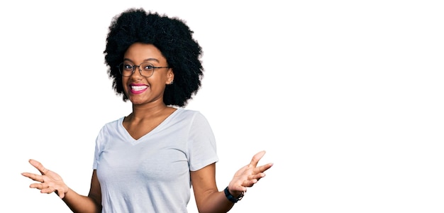 Photo gratuite jeune femme afro-américaine portant un t-shirt blanc décontracté souriant joyeux à bras ouverts comme accueil chaleureux salutations positives et confiantes