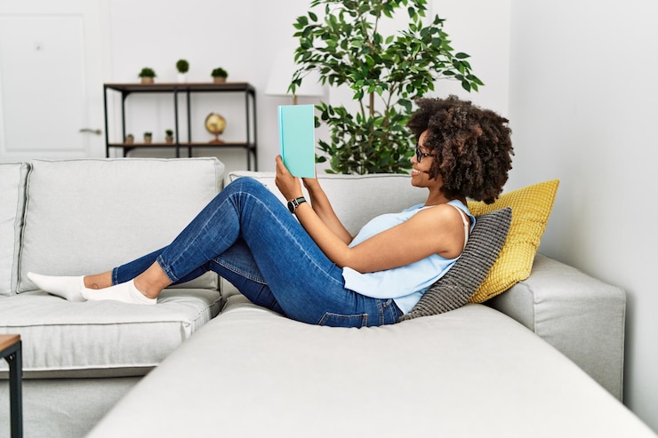 Photo gratuit jeune femme afro-américaine souriante confiante lisant un livre à la maison