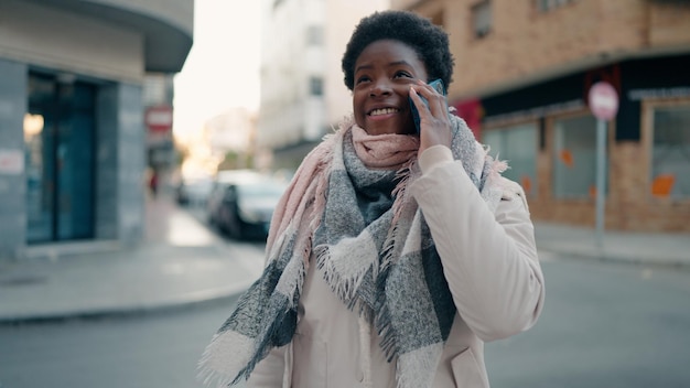 Photo gratuite jeune femme afro-américaine souriante confiante parlant sur le smartphone dans la rue