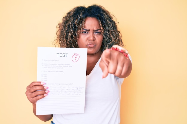 Photo gratuite jeune femme afro-américaine de taille plus montrant un examen raté pointant du doigt vers la caméra et vers vous, geste confiant à la recherche de sérieux