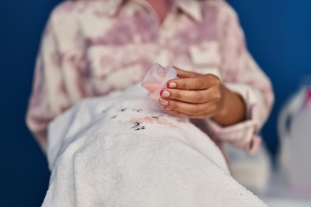 Photo gratuite jeune femme afro-américaine versant du détergent sur les vêtements à la lessive