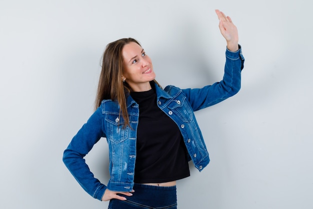 Jeune femme agitant la main pour dire au revoir en blouse, veste et l'air confiant. vue de face.